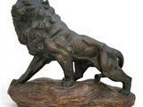 bronze statue of a lion on a rock on a white background