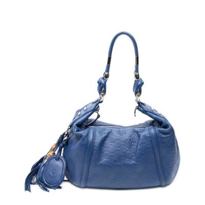 sac à main en cuir bleu orné de pompons sur fond blanc