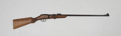 un gros plan d'un fusil posé contre un mur blanc, avec une crosse en bois