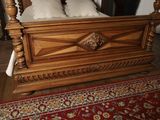 a wooden bed with white pillows and a red rug