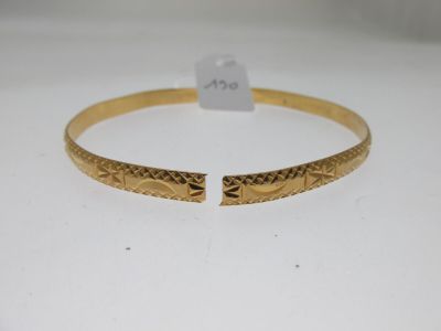 un bracelet rigide en or orné d'un motif gravé sur le côté