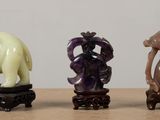 three figurines of elephants and a woman sitting on a table
