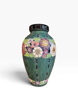 un vase vert sur lequel sont peintes des fleurs, sur un fond blanc