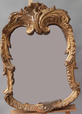 un miroir doré posé sur un socle en bois, sur fond gris