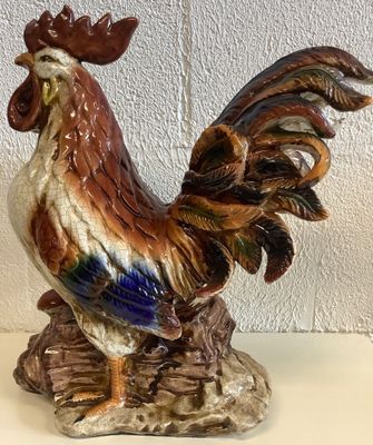 une figurine représentant un coq debout sur un rocher