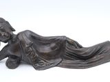 bronze statue of a woman laying on her stomach on a white background