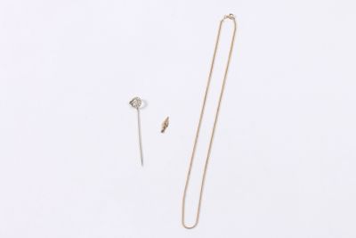 two necklaces and a pin are laying on a white surface