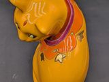 a yellow cat figurine sitting on a gray surface