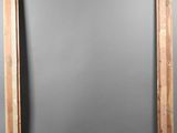 an old wooden frame with a mirror hanging on the wall