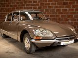 a brown car that is parked in front of a brick wall