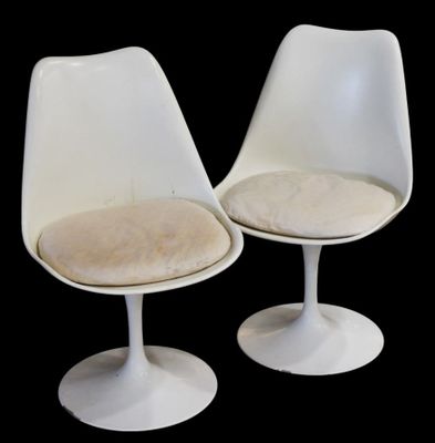 pair of white tulip chairs with beige cushions on a black background