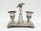 une image représentant un plateau en argent sur lequel sont posées deux bougies et un oiseau