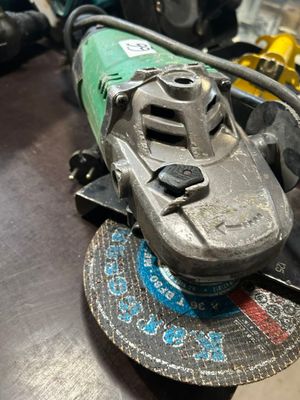 Quelqu'un utilise une meuleuse pour découper un morceau de métal posé sur une table.