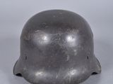 un vieux casque en acier posé sur une surface blanche, avec un fond gris