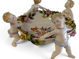 porcelain figurines of three cherensils holding a flowered bowl