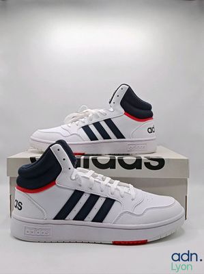 une paire de baskets blanches et bleues posée sur une boîte