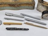 many different types of pens and pencils on the table