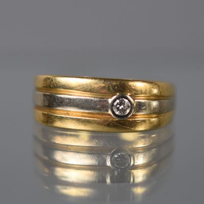 un gros plan d'une bague en or et diamants posée sur une surface réfléchissante
