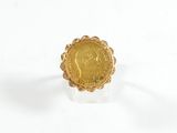 un gros plan d'une bague en forme de pièce d'or posée sur une surface blanche