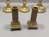 four brass candles are sitting on top of a white table