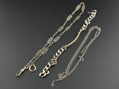 a group of three silver necklaces on a black surface