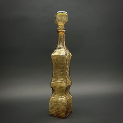 une bouteille en verre jaune avec un bouchon doré sur fond gris
