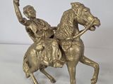 brass statue of a man riding a horse with a woman on the back