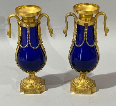 two blue vases with gold handles on a white surface