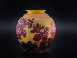 un vase jaune orné de fleurs rouges, posé sur un fond noir