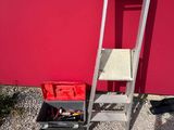 a ladder and a tool box next to a red wall