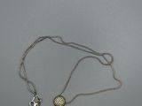 un collier en argent avec deux breloques sur une chaîne