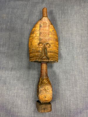 an old wooden object with a face on it on a gray surface