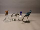 trois oiseaux en verre posés sur une table, à côté d'un vase en verre