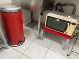 a microwave and a red trash can in a kitchen