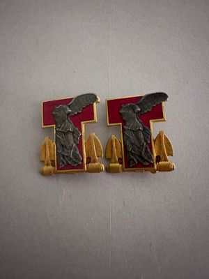 une paire de boucles d'oreilles rouges et dorées ornées d'une statuette représentant une femme tenant une épée