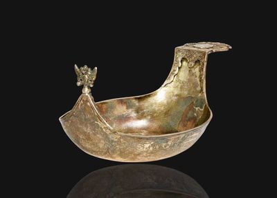 une image représentant un bol en bronze en forme de bateau, orné d'un oiseau sur le côté