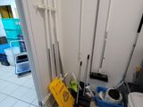 a bathroom with a toilet, a sink, and brooms on the floor