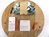 a wooden tray with a cosmetic bag and a bottle of lotion on it