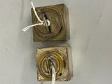 two metal objects hanging from a rope on the wall