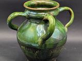 a green vase with two handles on a black background