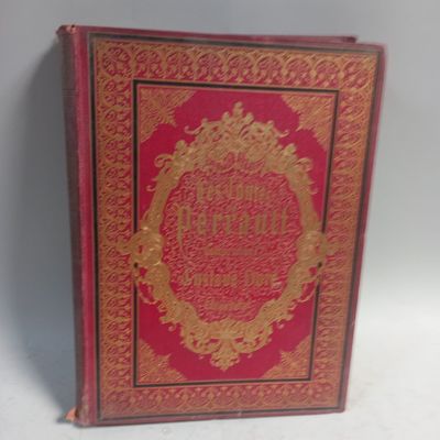 an old red book with gold writing on it sitting on a white surface