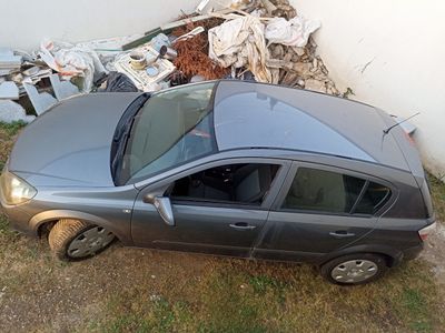 a car that is sitting in the grass next to a pile of trash