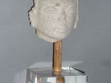 a stone head with a wooden stick on a stand