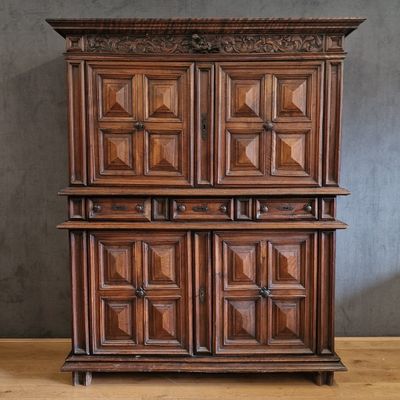 an old wooden cabinet with carved doors and drawers on a wooden floor
