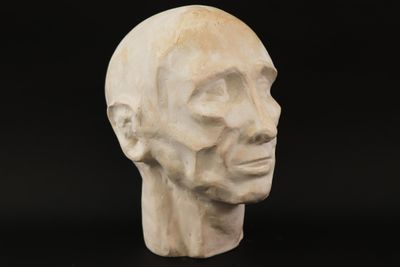 a close up of a sculpture of a man ' s head on a black background