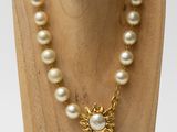 a close up of a necklace on a mannequin with pearls