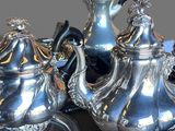 two silver teapots and a silver plate on a table