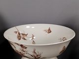 a white bowl with brown leaves on it on a stand