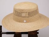 une photo d'un chapeau de paille posé sur un support en bois