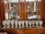 de nombreux verres posés sur une étagère en bois devant une fenêtre
